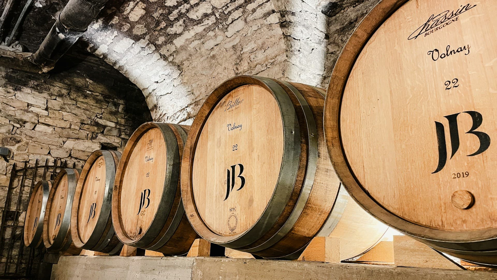 A row of oak wine barrels aging in a cellar