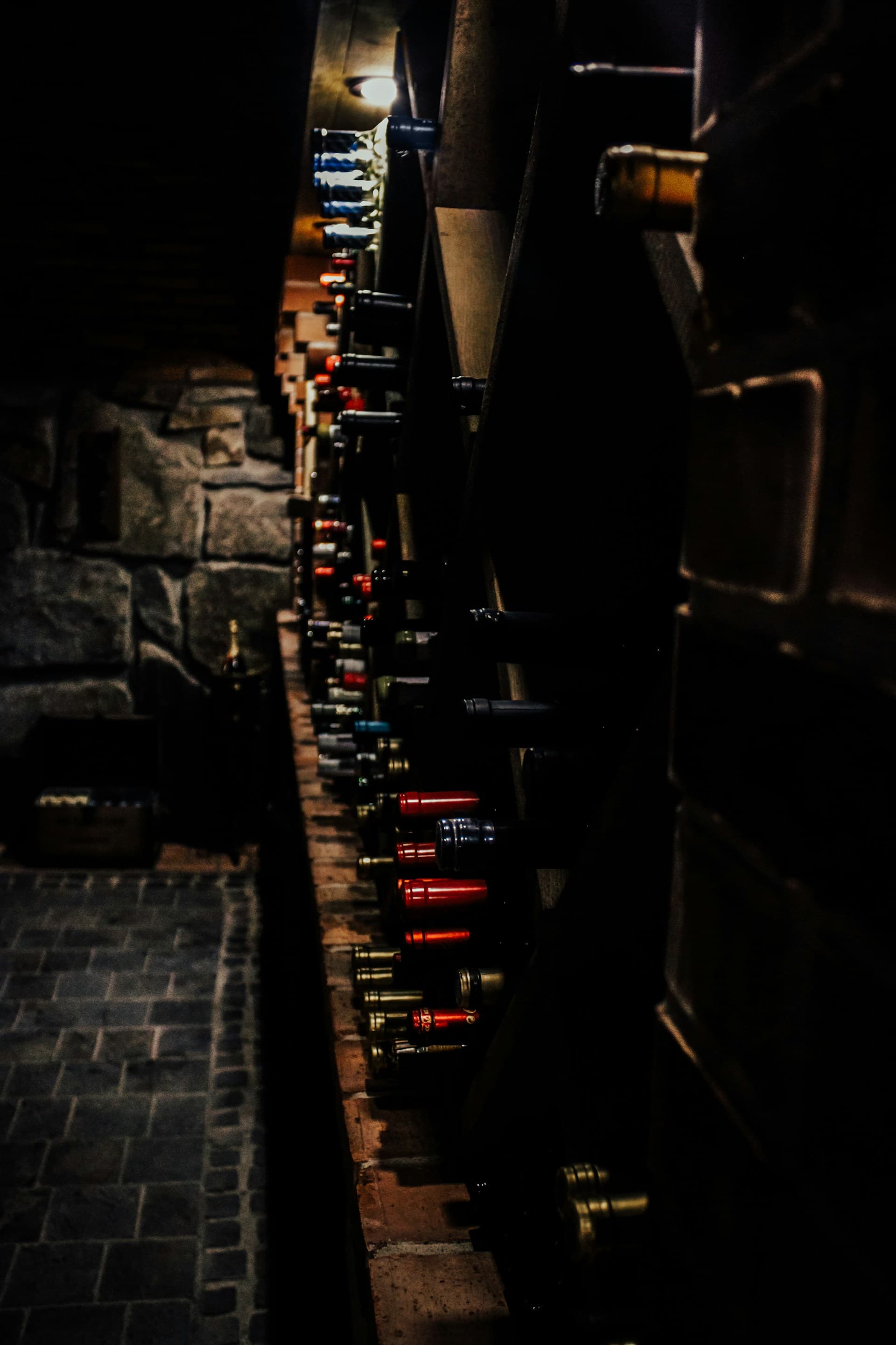 A long row of wine bottles lining a dimly lit wall