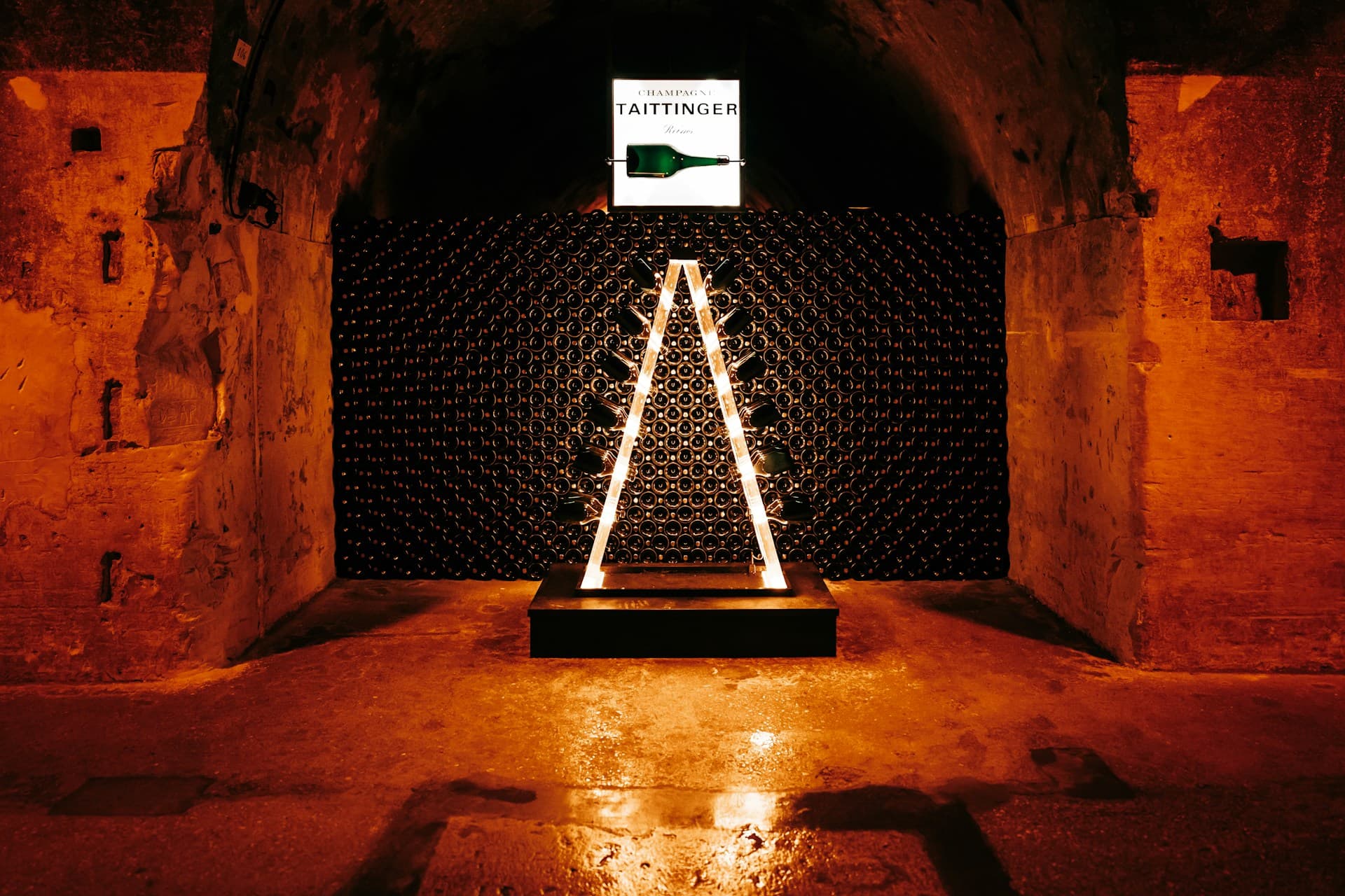 Dimly lit wine cellar with organized rows of bottles in wooden racks