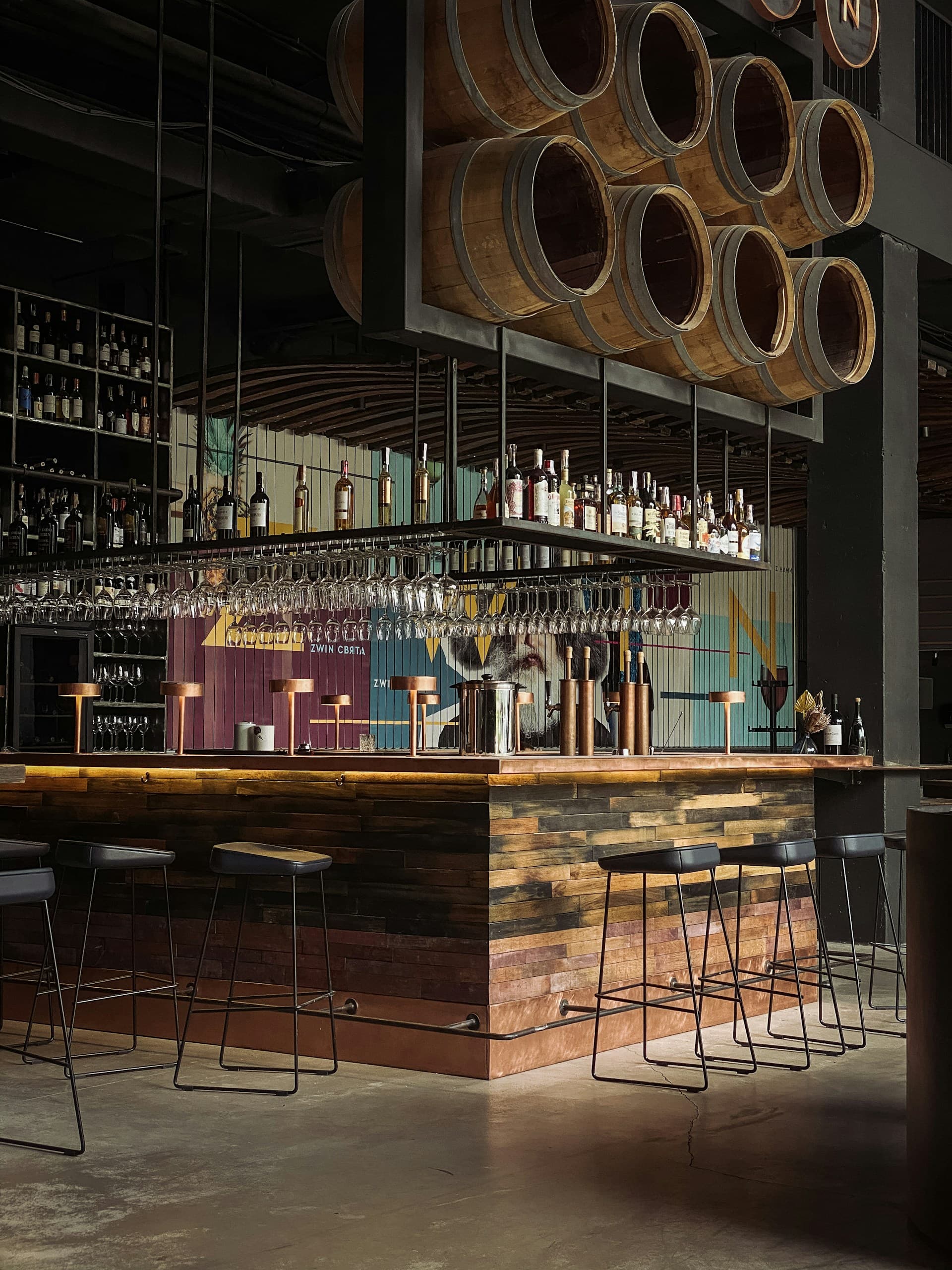 Warm wooden bar counter lined with wine bottles in soft light